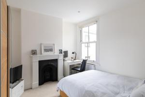 a bedroom with a bed and a desk and a fireplace at Stunning double bedroom in 4 bedroom house in Peckam in London