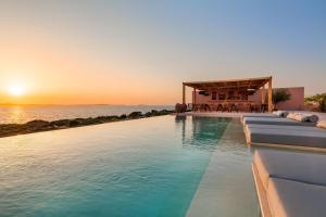 a swimming pool with a sunset in the background at Akre Hotel in Naxos Chora