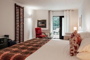 a bedroom with a white bed and a red chair at The Kent Motel in Niagara on the Lake