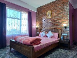 Cama en habitación con pared de ladrillo en Odyssey Stays Nongrim, Cherrapunji, en Cherrapunji