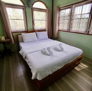 1 dormitorio con 2 cisnes en una cama con ventanas en บ้านห้วยลูกนกฟาร์มสเตย์ Banhuailuknok Farmstay en Ratchaburi
