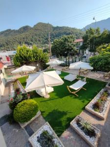 an outdoor patio with umbrellas and chairs and grass at Anassa Deluxe Apartments & Studios in Skala Potamias