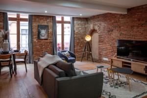 a living room with a couch and a brick wall at Le Passage de la Comédie - Climatisation & WiFi Fibre in Montauban