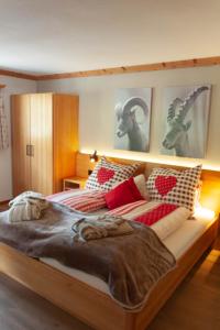 ザンクト・アンテーニーンにあるHotel Madrisajochのベッドルーム1室(大型ベッド1台、赤と白の枕付)