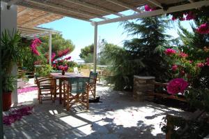 - une terrasse avec une table, des chaises et des fleurs dans l'établissement Eleonas Apartments, à Sifnos