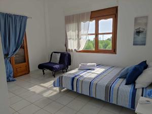 1 dormitorio con cama, ventana y silla en Gaia Olives Villa, en Sozopoli
