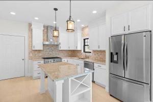 una cucina con armadi bianchi e frigorifero in acciaio inossidabile di Stylist East Hampton Home a East Hampton