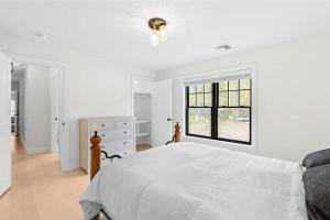 una camera bianca con un letto e una finestra di Stylist East Hampton Home a East Hampton