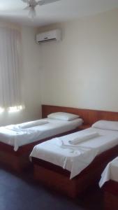 a hotel room with two beds and two lamps at Hotel Alvorada in Goiânia