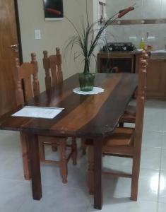 una mesa de madera con sillas y un jarrón con una planta en Posadas Centro en Posadas