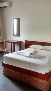 a large bed in a room with a table at Hotel Alvorada in Goiânia