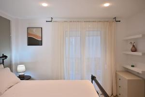 1 dormitorio con cama blanca y ventana en Seabreeze apartment in Palaio Faliro/ Netflix, en Atenas