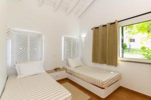 two beds in a room with a window at Pedras D'el Rei in Tavira
