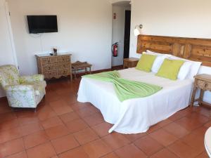 a bedroom with a large white bed and a chair at Algarve Beachfront Alvor in Alvor