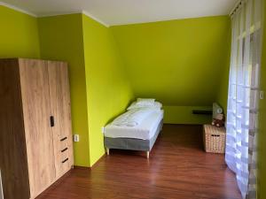 Öskü的住宿－Ada Vendégház，一间拥有绿色墙壁的卧室和一张位于客房内的床