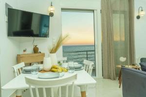 a white dining room with a view of the ocean at Cocoscape Suite, seaside & 270° open view in Kalamaki Heraklion