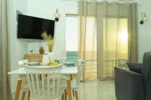 a living room with a table and chairs and a television at Cocoscape Suite, seaside & 270° open view in Kalamaki