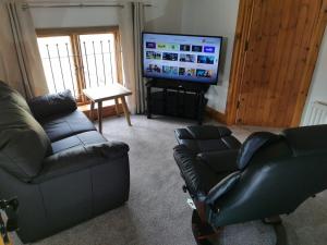 a living room with a couch and a tv at The Sanctuary at Boningale Manor in Wolverhampton