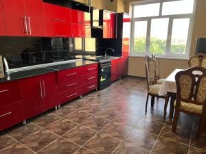 a kitchen with red cabinets and a table and chairs at Major Guest House in Fergana