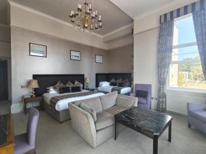 a hotel room with a bed and a couch and a chandelier at Abbey Sands Hotel in Torquay