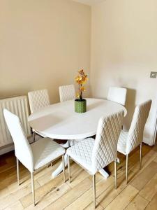 a white table and chairs with a vase on it at JB Stays Croydon Townhouse in South Norwood +2 photos