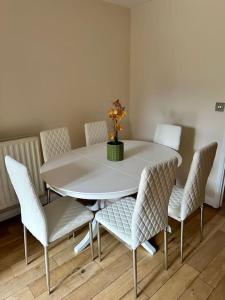 a white table with chairs and a vase of flowers on it at JB Stays Croydon Townhouse in South Norwood