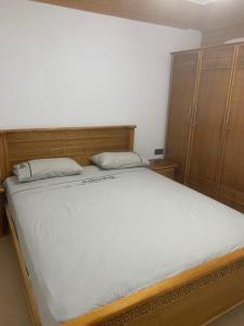 a bedroom with a large white bed and wooden cabinets at Appartement familial Al hoceima in Al Hoceïma