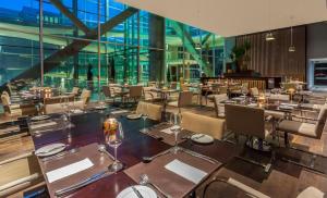 un restaurante con mesas, sillas y ventanas de cristal en Four Points By Sheraton Los Angeles en Los Ángeles