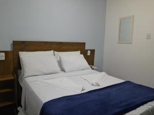 un letto con lenzuola bianche e una coperta blu sopra di Casa de Temporada Ceu e Mar a Praia do Bananal