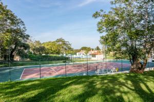 a tennis court in a park with a tree at Pedras D'el Rei in Tavira