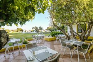 a patio with tables and chairs and trees at Pedras D'el Rei in Tavira