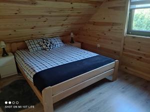 1 dormitorio con 1 cama en una cabaña de madera en Domek Pod Sosnami, en Tomaszów Lubelski