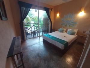 a bedroom with a bed and a balcony with a table at Eco Hotel Casa Corazón Bacalar in Bacalar