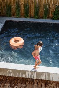 a young child in a swimming pool with a toilet at B.Hostel in Comporta
