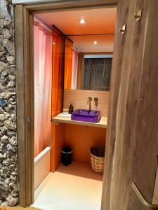een badkamer met een paarse wastafel en een spiegel bij Studio Senang in Nijmegen