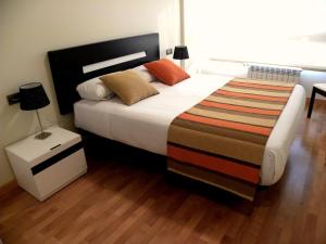 a bedroom with a large bed with a striped blanket at Apartamentos Albatros in Barro de Llanes