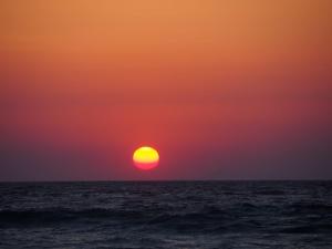 una puesta de sol naranja sobre el océano en Nautilus Beach House, en Paradeísion