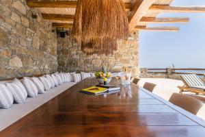 una mesa larga en una habitación con una pared de piedra en Villa Olivia Mykonos en Agios Stefanos