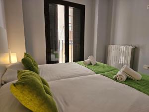 1 dormitorio con 2 camas, sábanas verdes y toallas en IMEDA Apartamentos Piedra Santa, en Granada