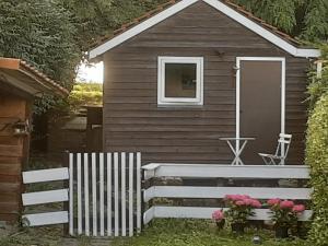 una pequeña casa con una valla blanca y flores en Villa commune PoldersView en Sluis