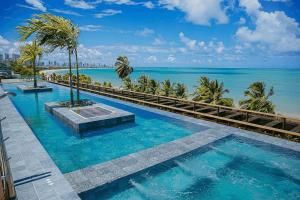 a swimming pool with a view of the ocean at Unity #325 - Conforto em Cabo Branco por Carpediem in Penha