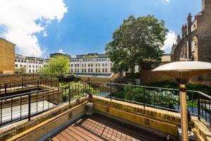 a balcony with an umbrella and some buildings at Luxury 4 bed house in Belgravia Knightsbridge in London