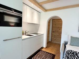 una pequeña cocina con fregadero y una cama en una habitación en Natur, Erholung, moderne 35m2 für 2P mit Auto PP - SP19, en Pontresina