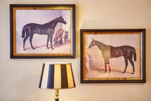 zwei gerahmte Gemälde eines Pferdes an der Wand in der Unterkunft Romantik Alpenhotel Waxenstein in Grainau