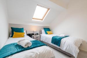 two beds in a room with a window at Deluxe Apartment in Sheffield City Centre - Sleeps 6 in Sheffield