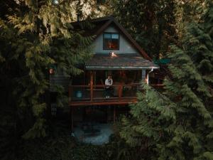 un homme debout sur le pont d'une cabane dans les arbres dans l'établissement Chase's River Cabin, à Granite Falls