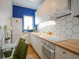 eine Küche mit weißen Schränken und einer blauen Wand in der Unterkunft Bosman Place Szczecin in Stettin