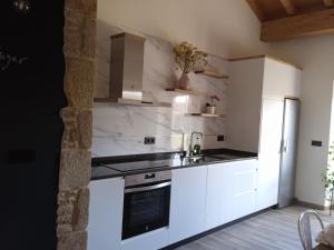 Una cocina blanca con fregadero y refrigerador. en Casona de ventas, en Portomarín 7 fotos más