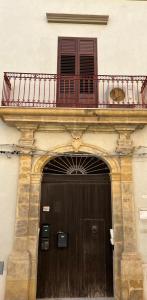 un edificio con porta in legno e balcone di Sisters appartamenti a Castelvetrano Selinunte