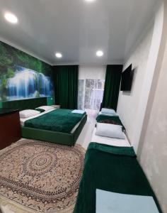 2 Betten in einem Zimmer mit grünen Vorhängen in der Unterkunft Гостевой дом ЛОНТАНА in Gagra